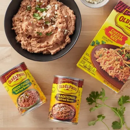A pan of Old El Paso Rice & Beans on a wooden table surrounded by packages of the same