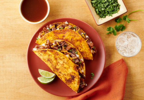 Serve tacos with seasoned broth: a plate featuring two tacos accompanied by a small bowl of salsa for dipping.